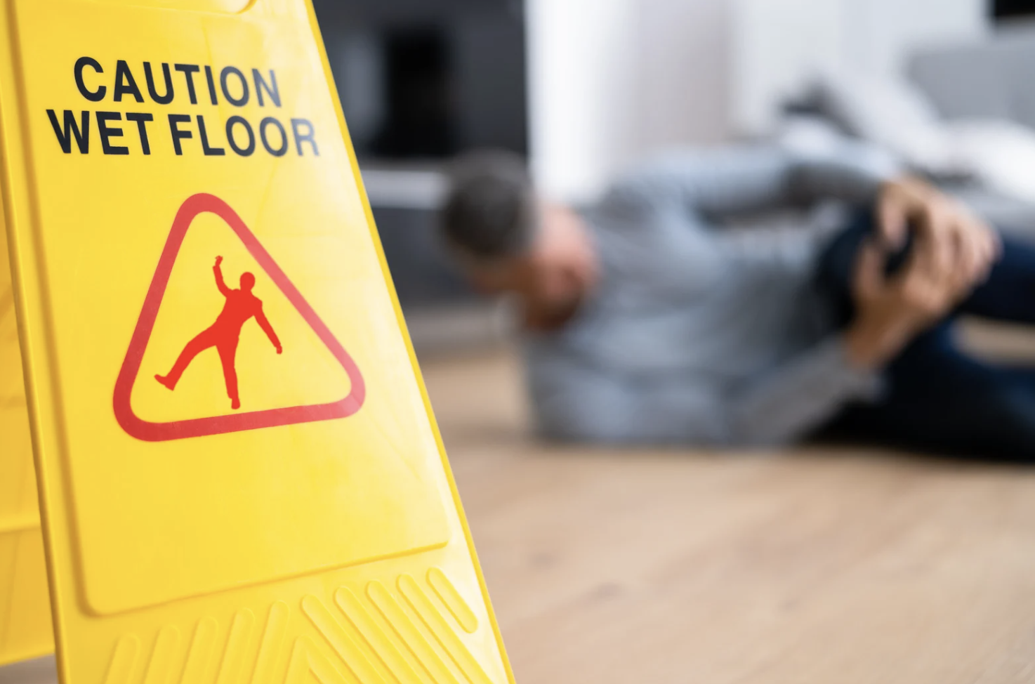 caution wet floor sign with injured person in the background